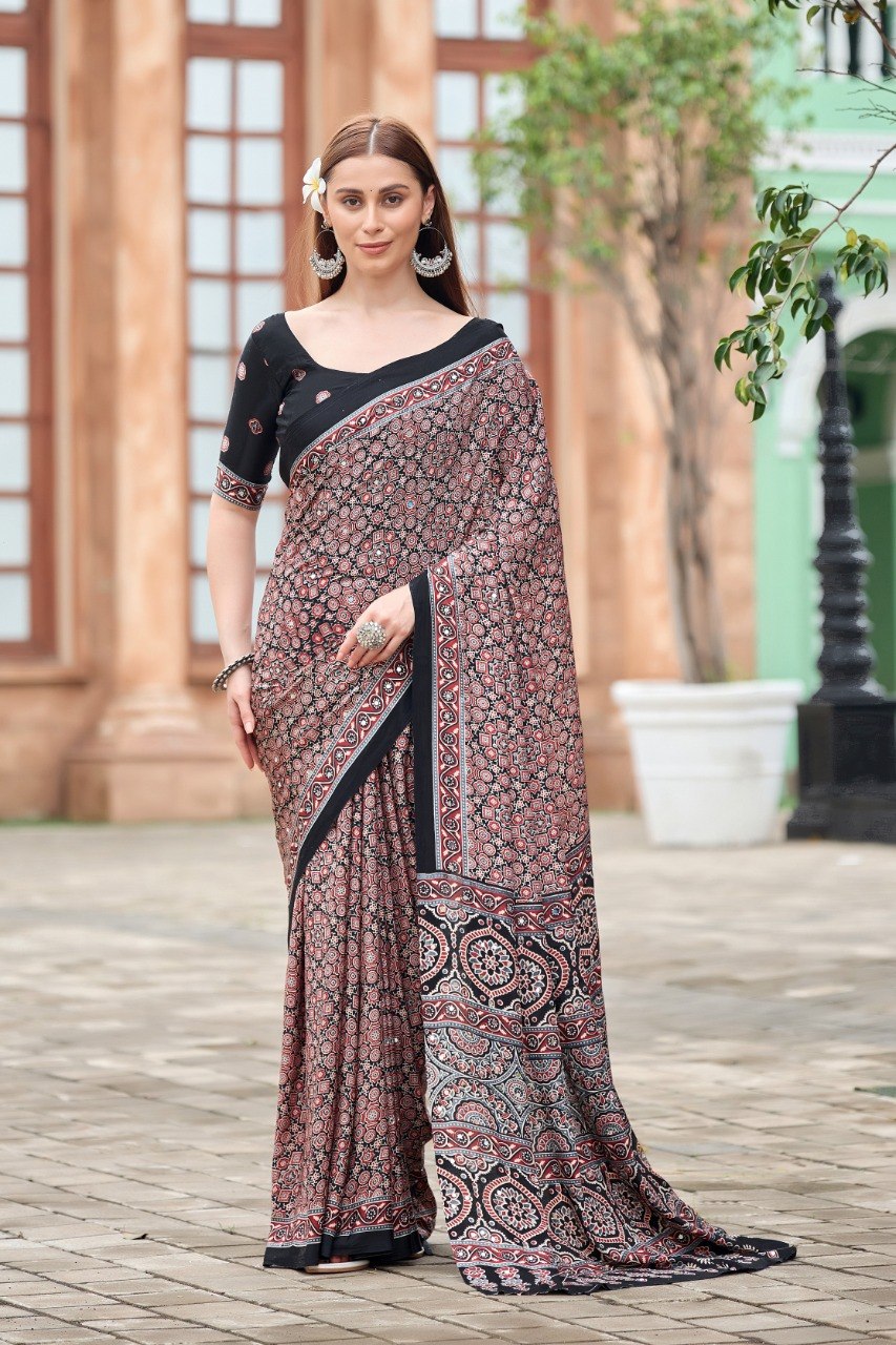 Woman wearing a black Ajrakh print mirror work Italian crepe saree with floral border and matching blouse — Chandrikas