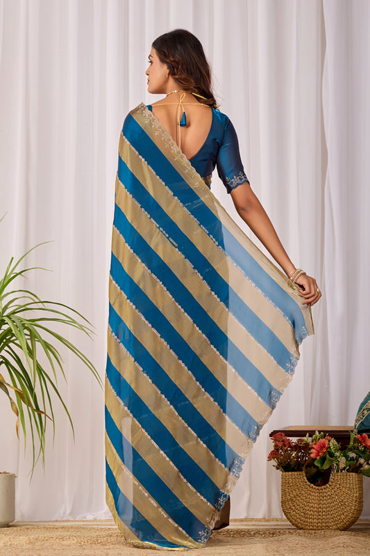 Woman in back pose wearing cobalt blue striped satin patta saree with golden border — Chandrikas