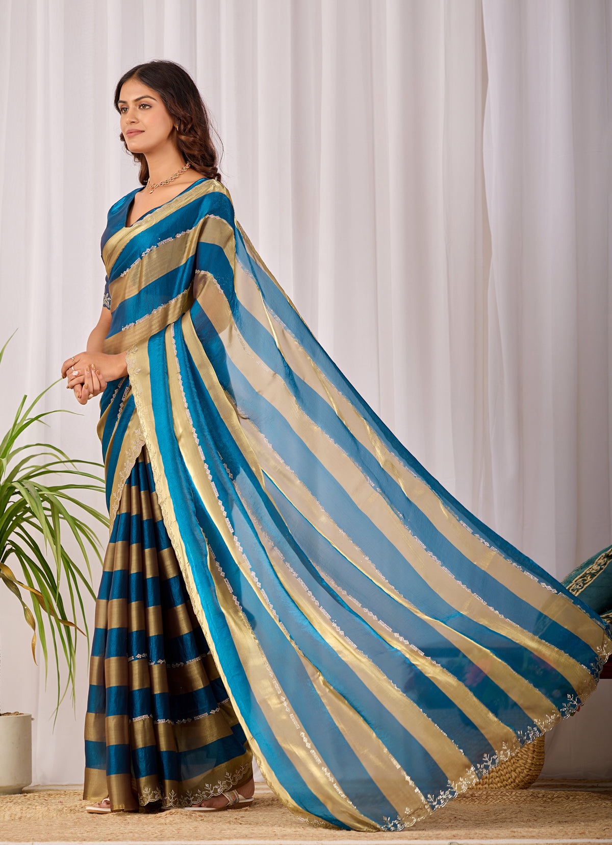 Woman in side pose wearing cobalt blue striped satin patta saree with golden border — Chandrikas
