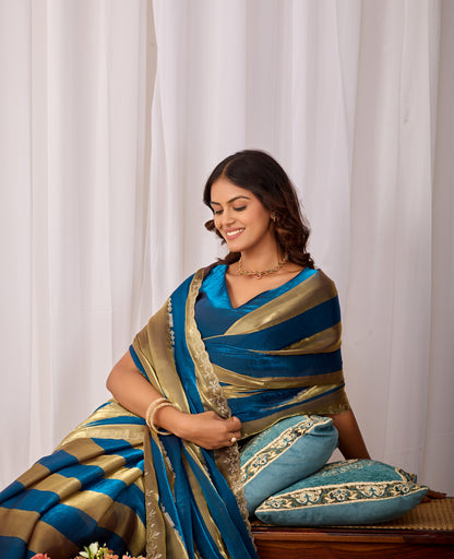 Woman in sitting pose wearing cobalt blue striped satin patta saree with golden border — Chandrikas