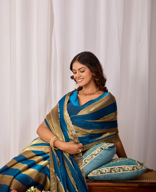 Woman in sitting pose wearing cobalt blue striped satin patta saree with golden border — Chandrikas