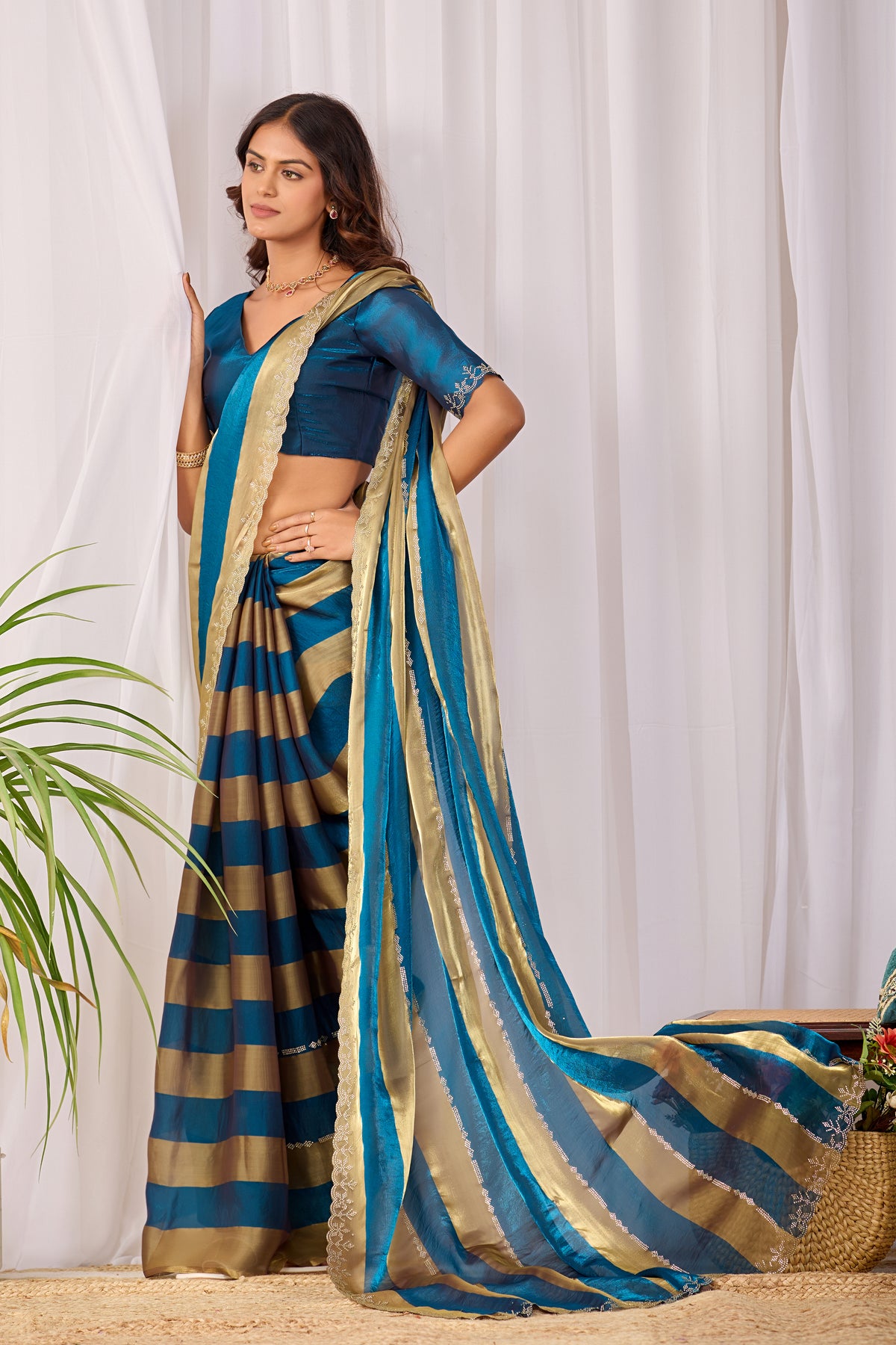 Woman in standing pose wearing cobalt blue striped satin patta saree with golden border — Chandrikas