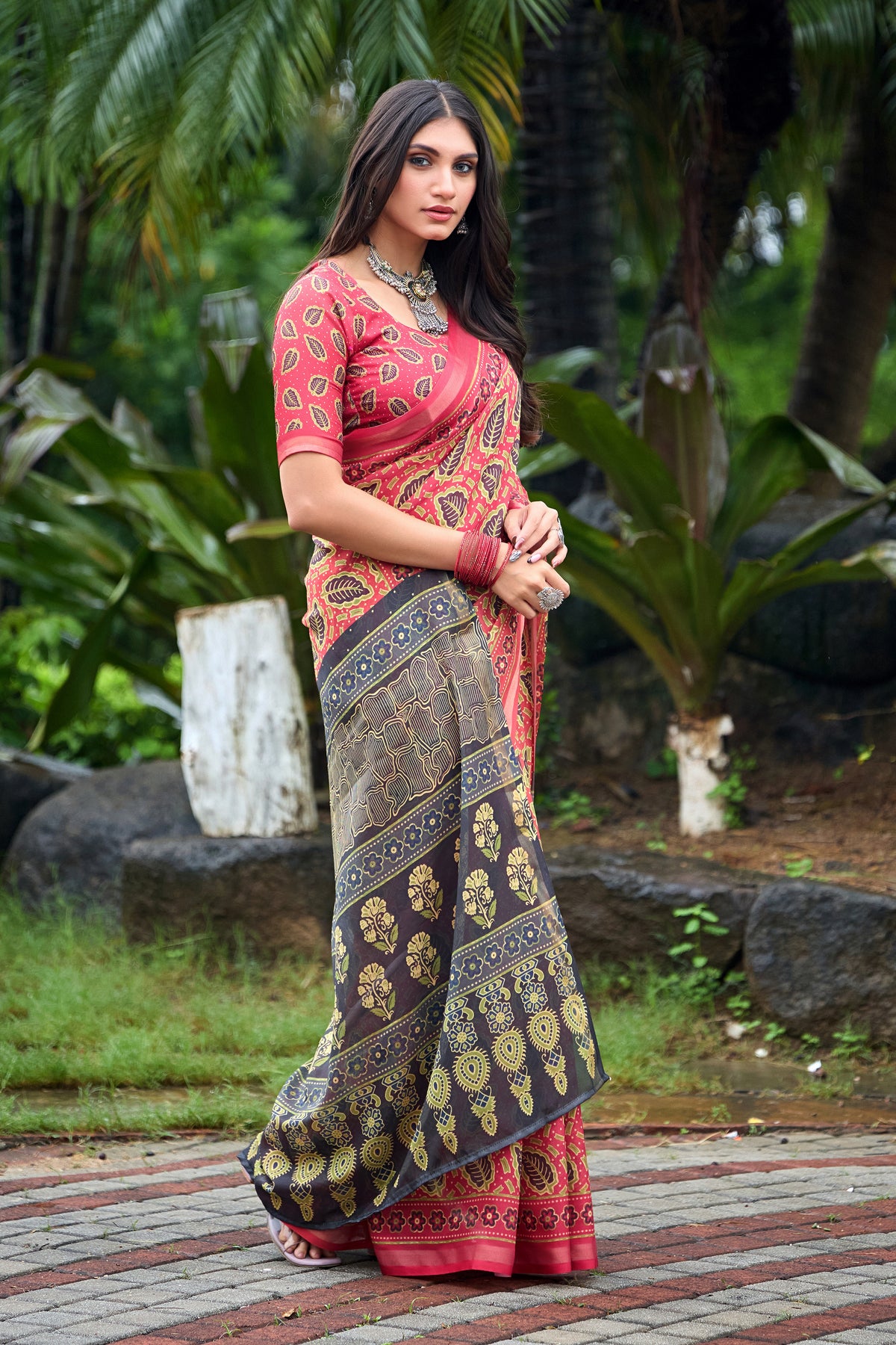 Woman in standing pose wearing coral red leaf print cotton saree with grey pallu — Chandrikas