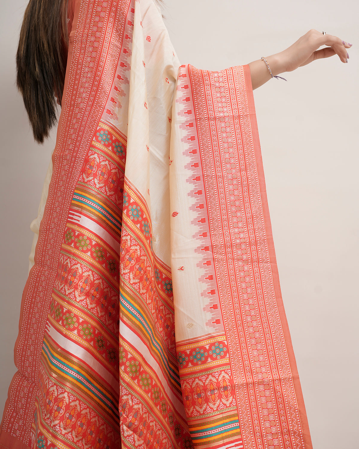 Close-up of cream coral Assam cotton silk saree pallu with geometric rosette and multi-colour stripes — Chandrikas