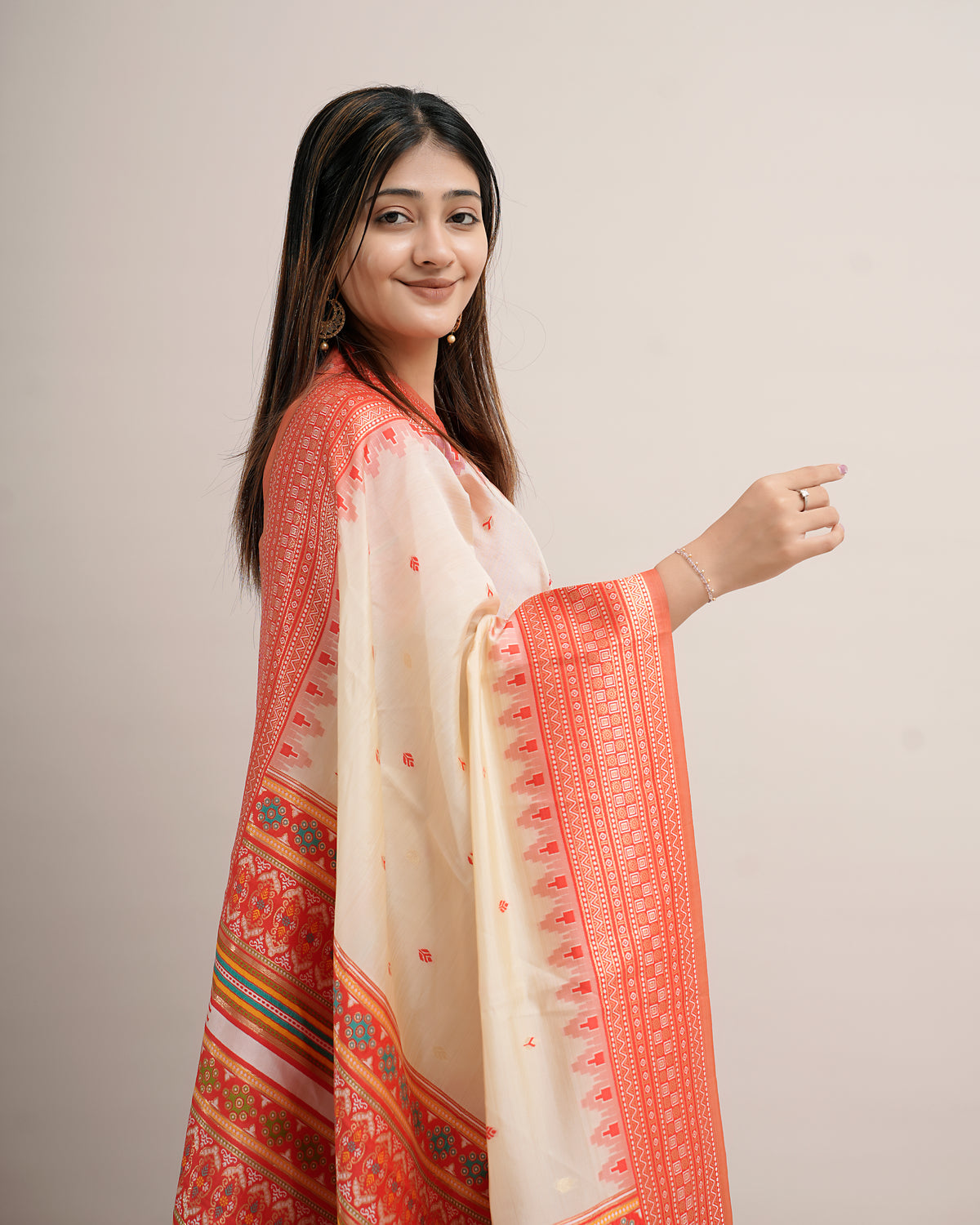 Woman in side pose draping cream coral Assam cotton silk saree with rosette pallu — Chandrikas