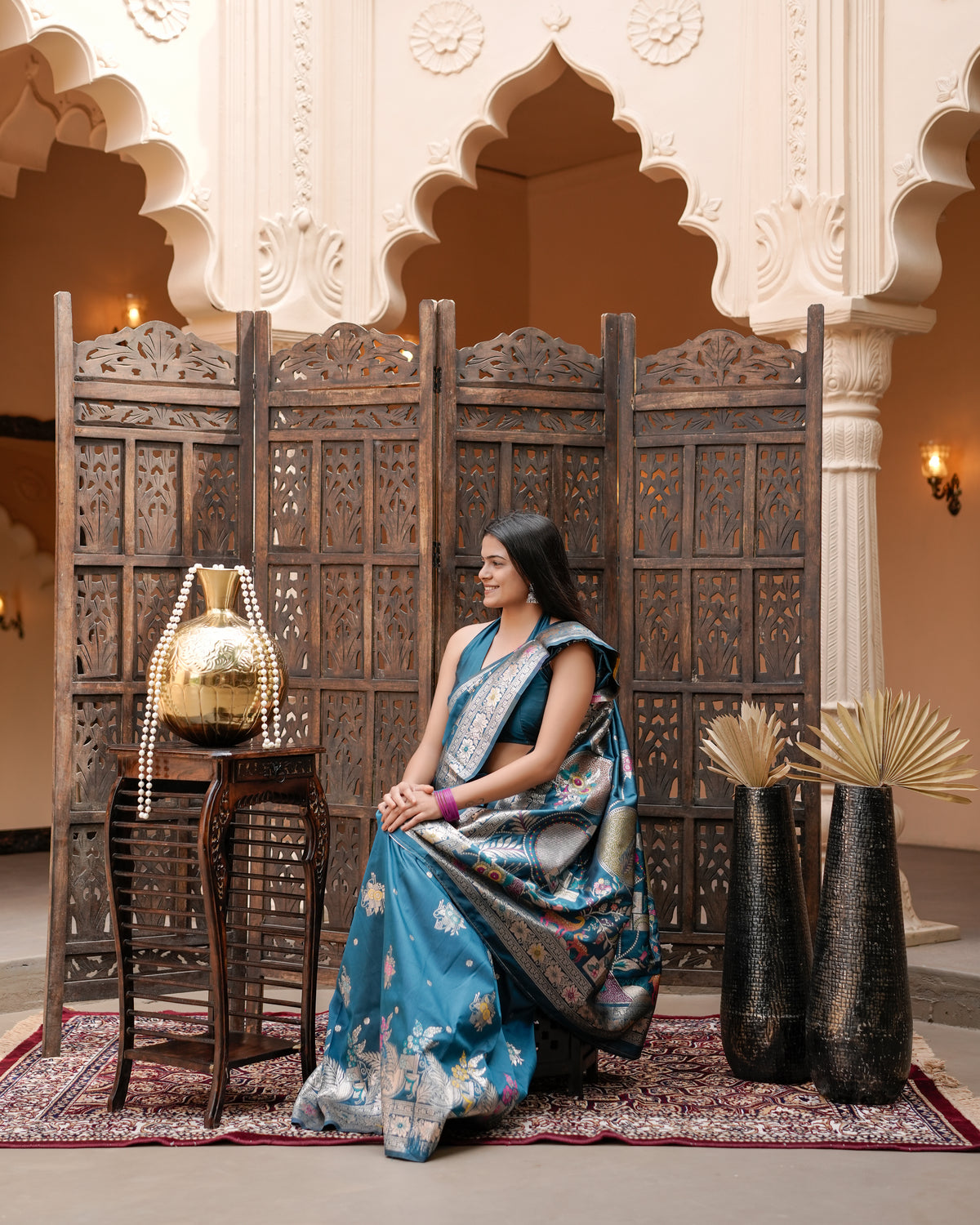 Woman seated showing pallu of deep teal blue Meenakari deer motif zari pallu silk saree — Chandrikas