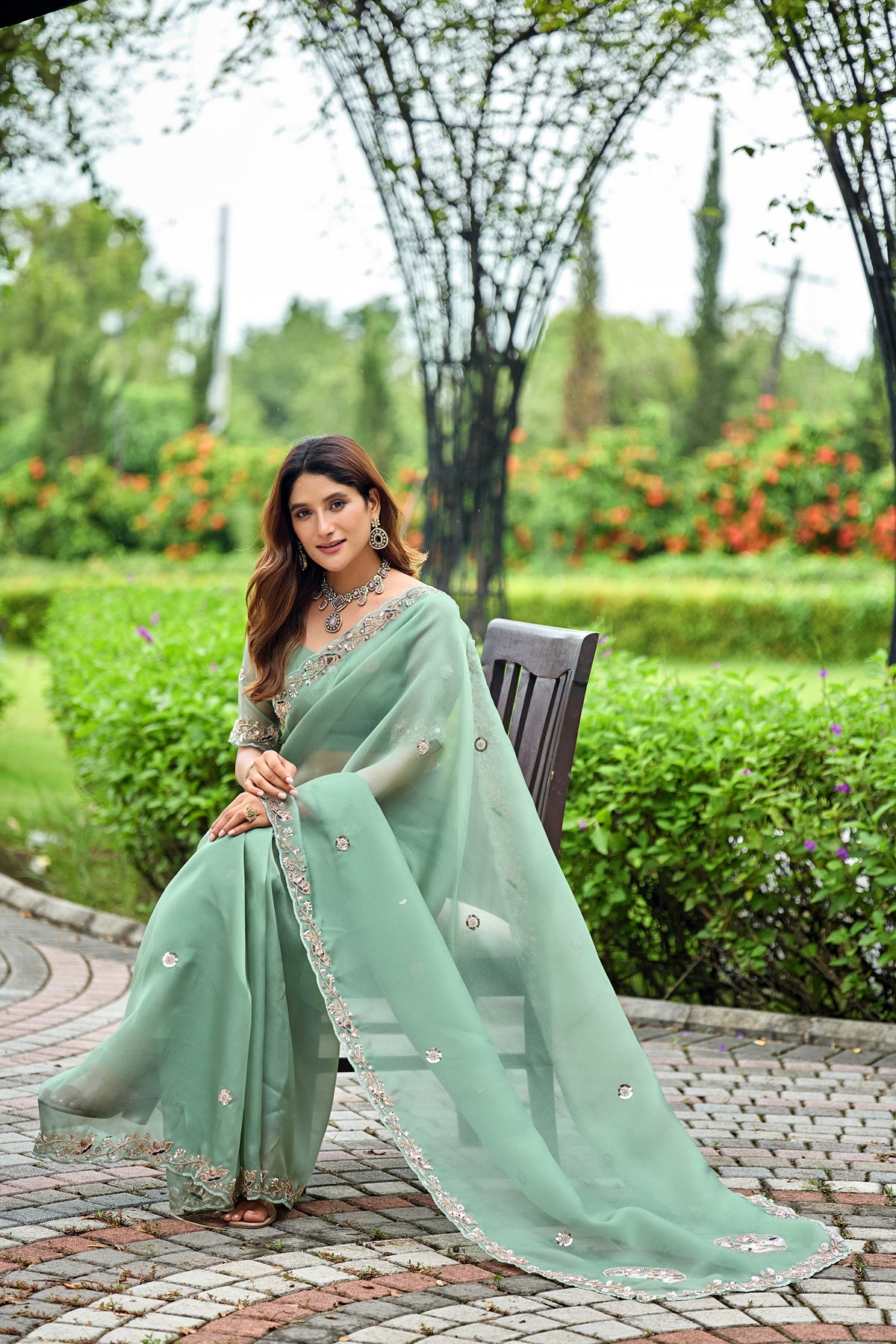 Woman in sitting pose wearing dusty rama sequin floral embroidered tissue silk saree — Chandrikas