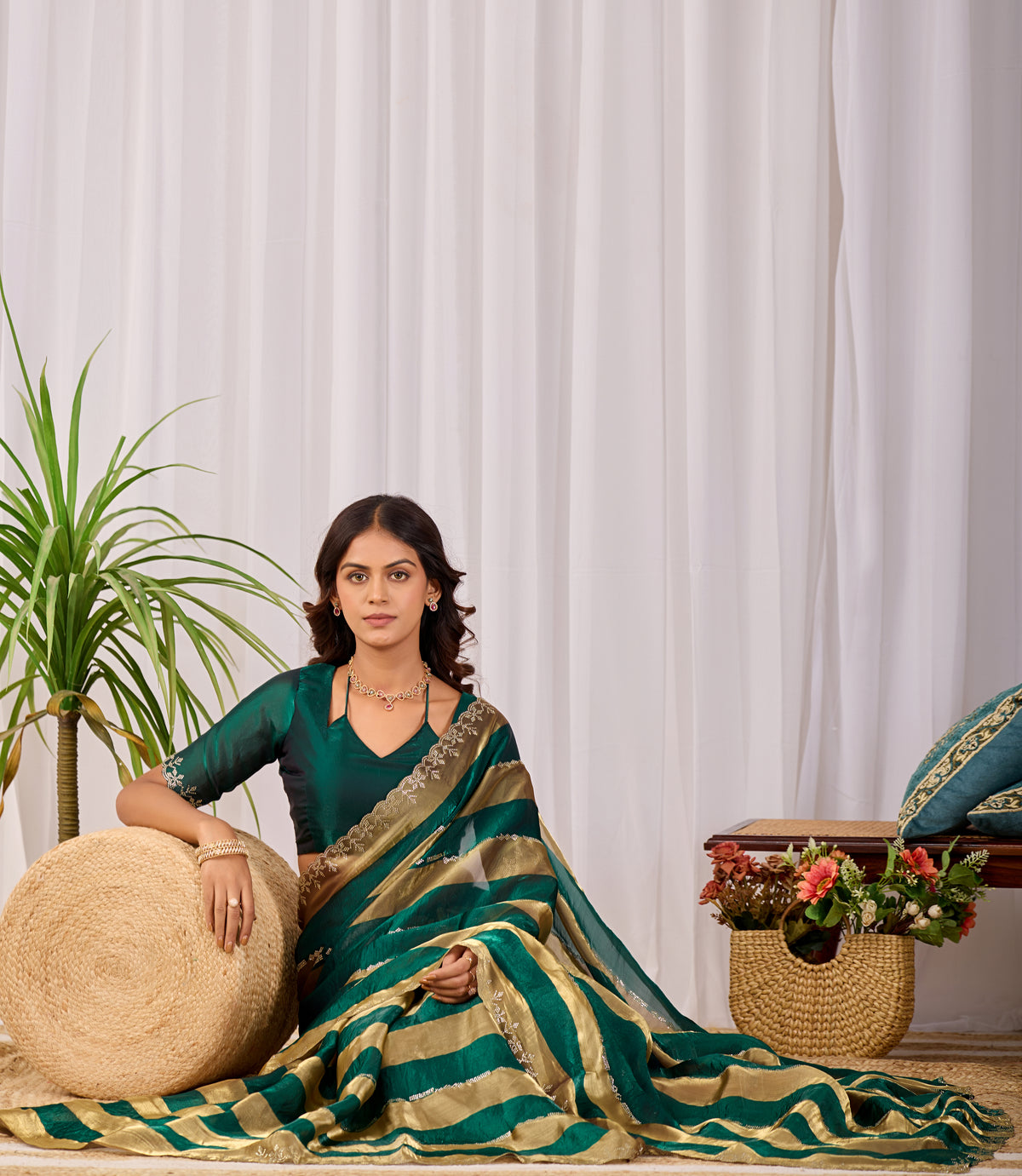 Woman in sitting pose wearing emerald green striped satin patta saree with golden border — Chandrikas
