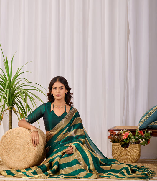 Woman in sitting pose wearing emerald green striped satin patta saree with golden border — Chandrikas