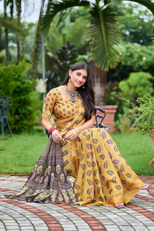 Woman in sitting pose wearing golden mustard leaf print cotton saree with brown border — Chandrikas