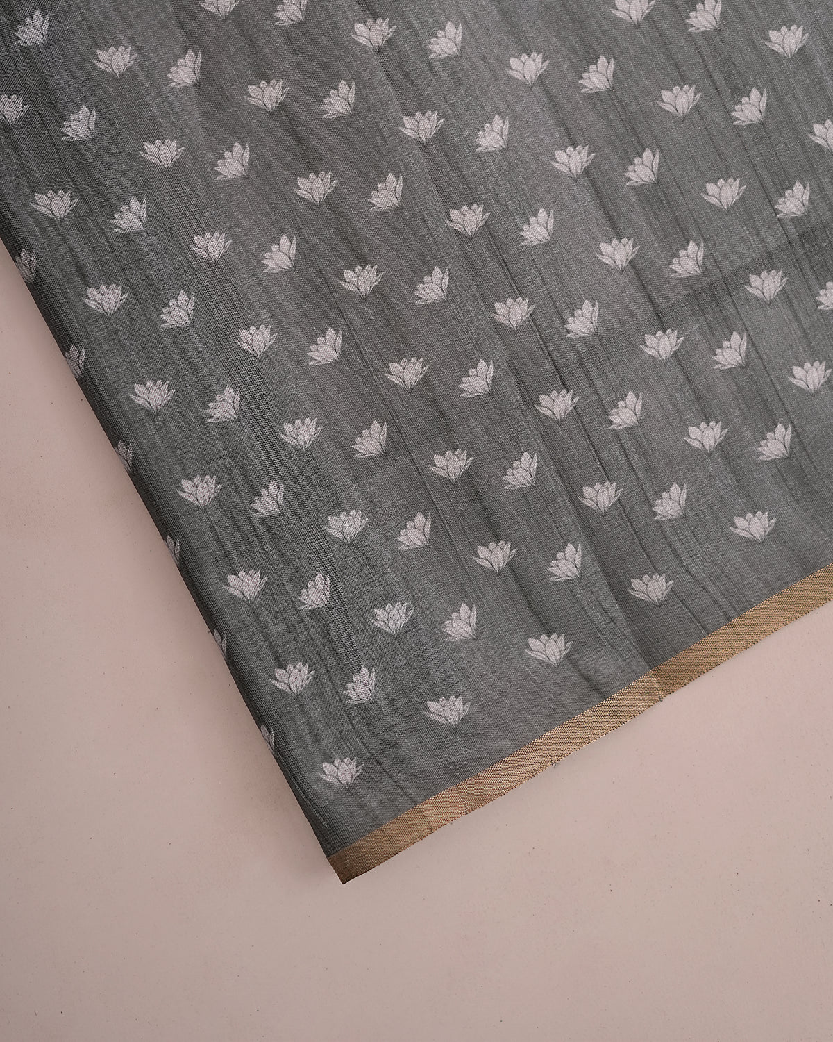 Close-up of grey cotton saree fabric showing woven lotus floral buttis and gold border — Chandrikas