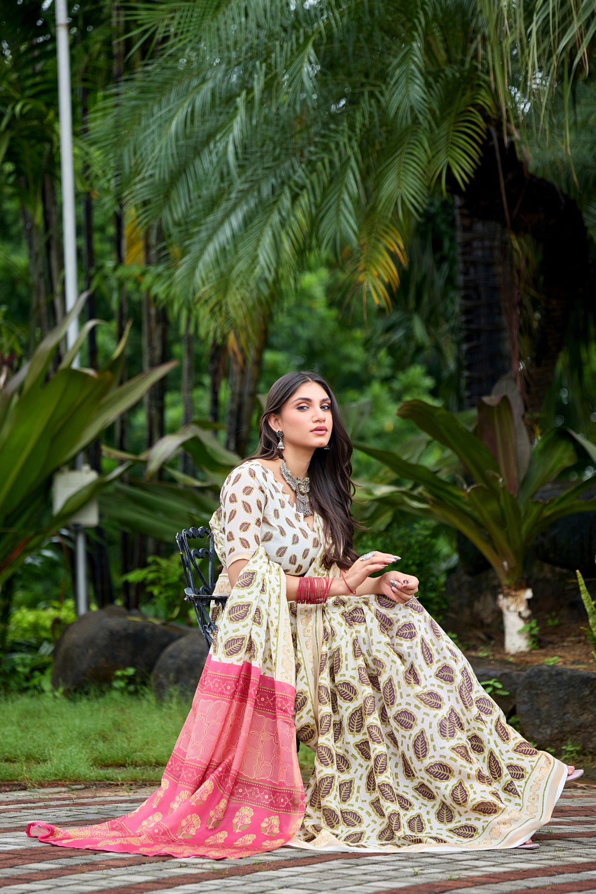 Woman in sitting pose wearing ivory cream leaf print cotton saree with pink border — Chandrikas