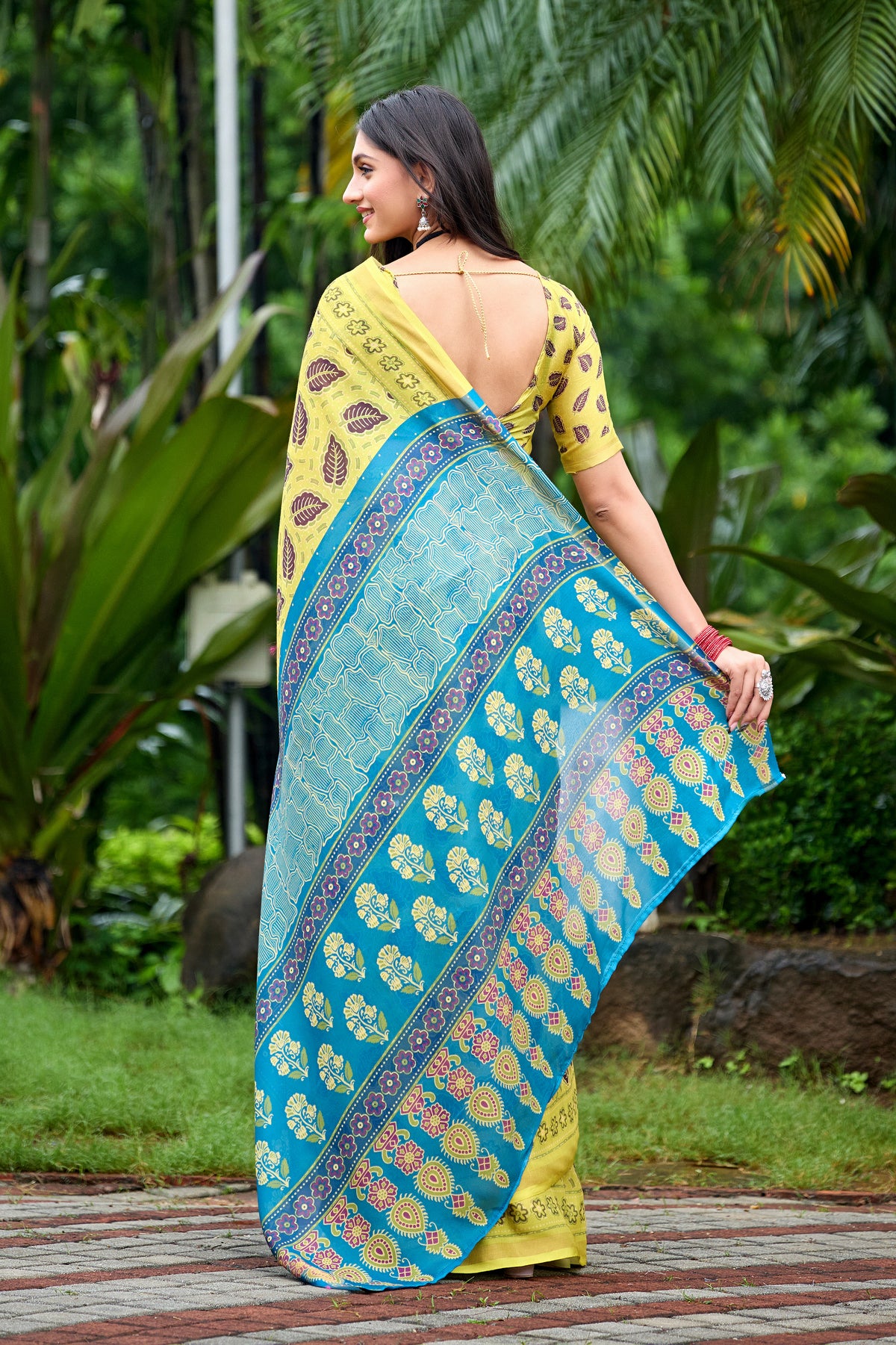 Woman in back pose wearing lemon yellow leaf print cotton saree with blue border — Chandrikas
