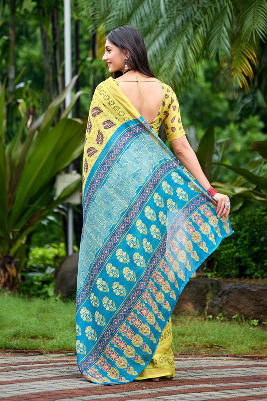 Woman in back pose wearing lemon yellow leaf print cotton saree with blue border — Chandrikas