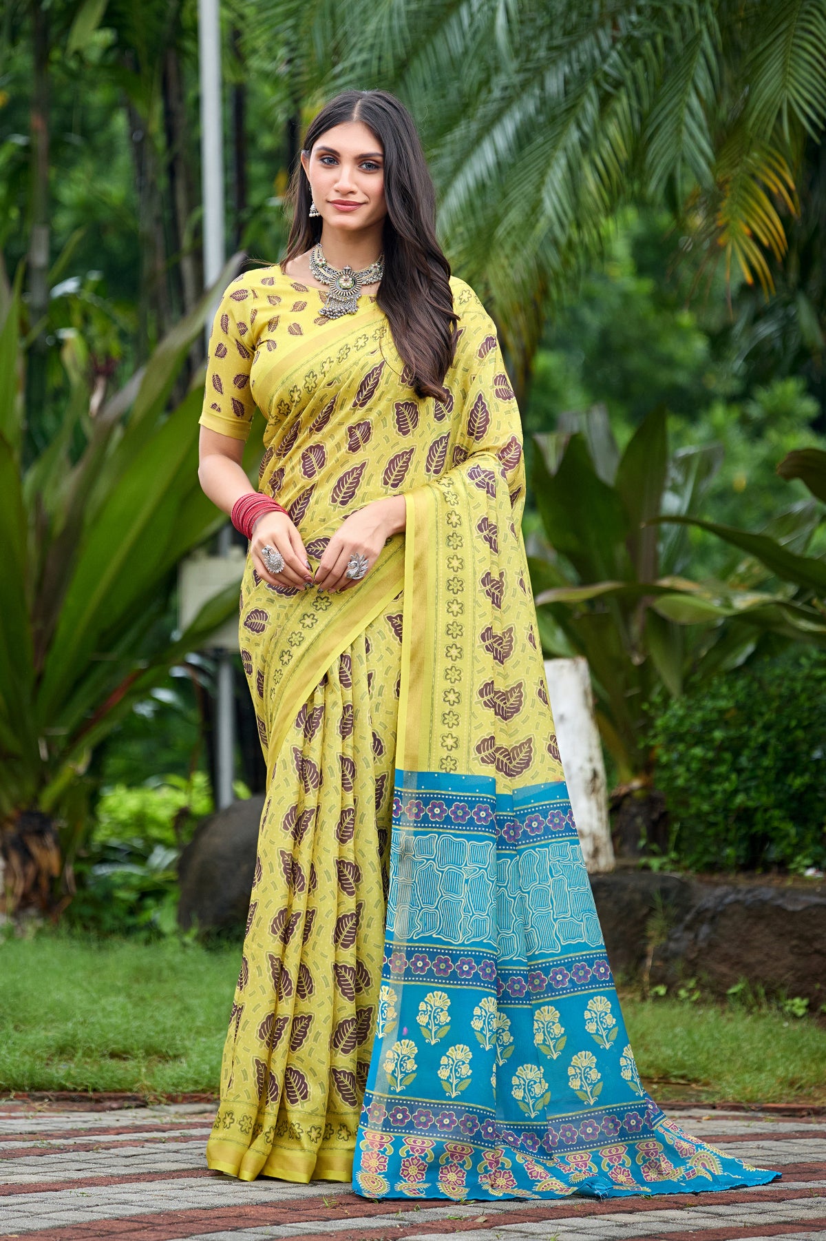 Woman in front pose wearing lemon yellow leaf print cotton saree with blue border — Chandrikas