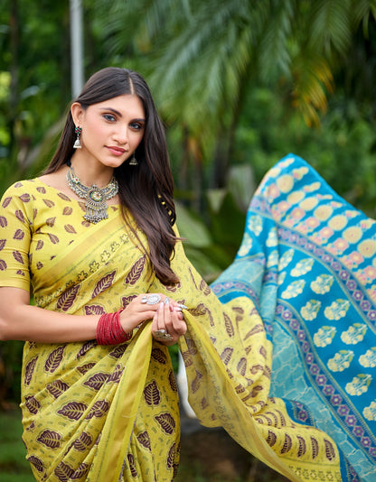 Woman in side pose wearing lemon yellow leaf print cotton saree with blue border — Chandrikas