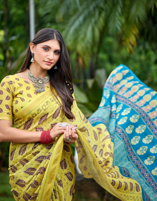 Woman in side pose wearing lemon yellow leaf print cotton saree with blue border — Chandrikas