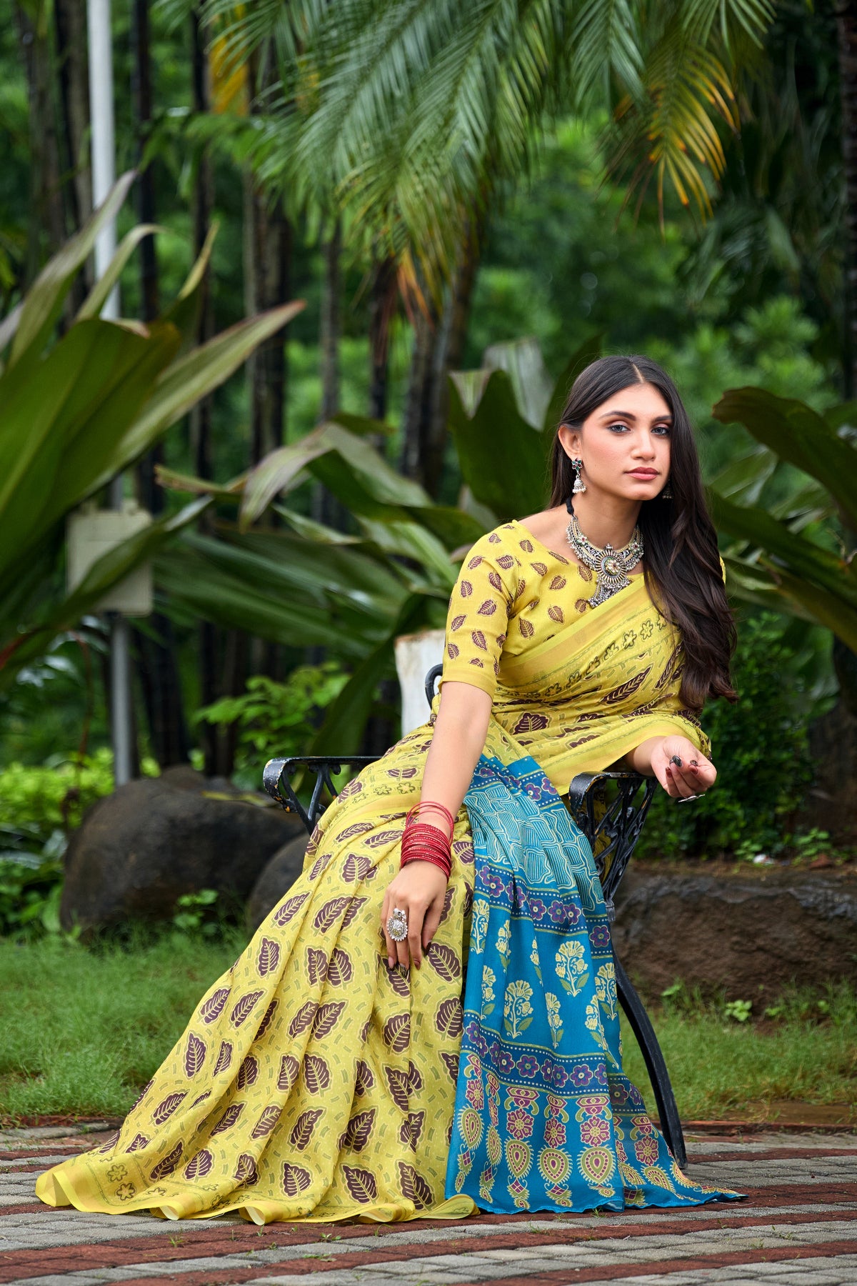 Woman in sitting pose wearing lemon yellow leaf print cotton saree with blue border — Chandrikas