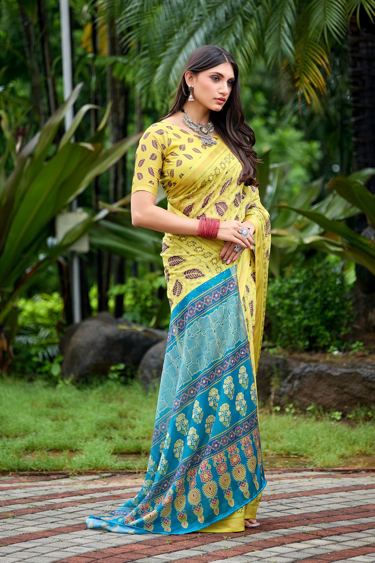 Woman in standing pose wearing lemon yellow leaf print cotton saree with blue pallu — Chandrikas