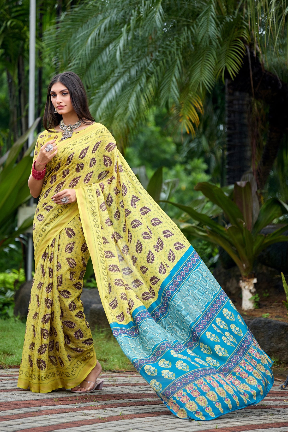 Woman in walking pose wearing lemon yellow leaf print cotton saree with blue border — Chandrikas