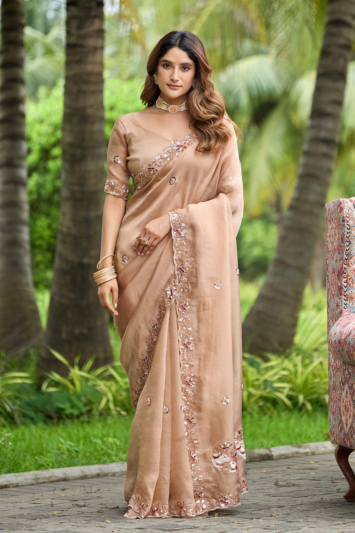 Woman standing in front pose wearing light chicku sequin floral embroidered tissue silk saree — Chandrikas