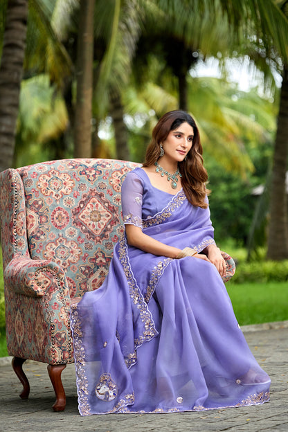 Woman in sitting pose on chair wearing light lavender sequin floral embroidered tissue silk saree — Chandrikas