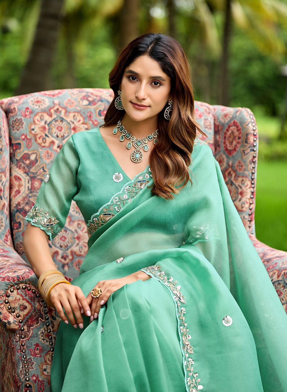 Woman in sitting pose wearing light rama sequin floral embroidered tissue silk saree — Chandrikas