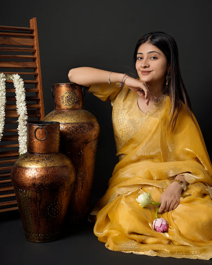 Woman in close seated pose wearing mustard yellow tissue crepe silk saree with scalloped border — Chandrikas