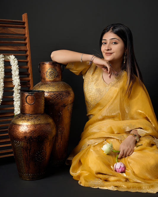 Woman in close seated pose wearing mustard yellow tissue crepe silk saree with scalloped border — Chandrikas