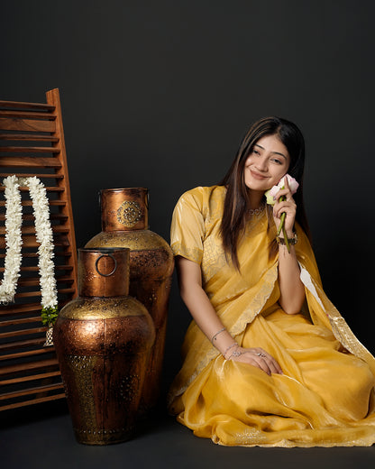 Woman in seated pose wearing mustard yellow tissue crepe silk saree with scalloped border — Chandrikas