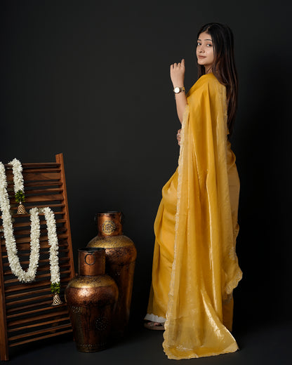 Woman in side pose wearing mustard yellow tissue crepe silk saree with scalloped border — Chandrikas