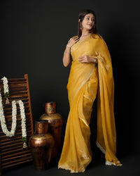 Woman in standing pose wearing mustard yellow tissue crepe silk saree with scalloped border — Chandrikas