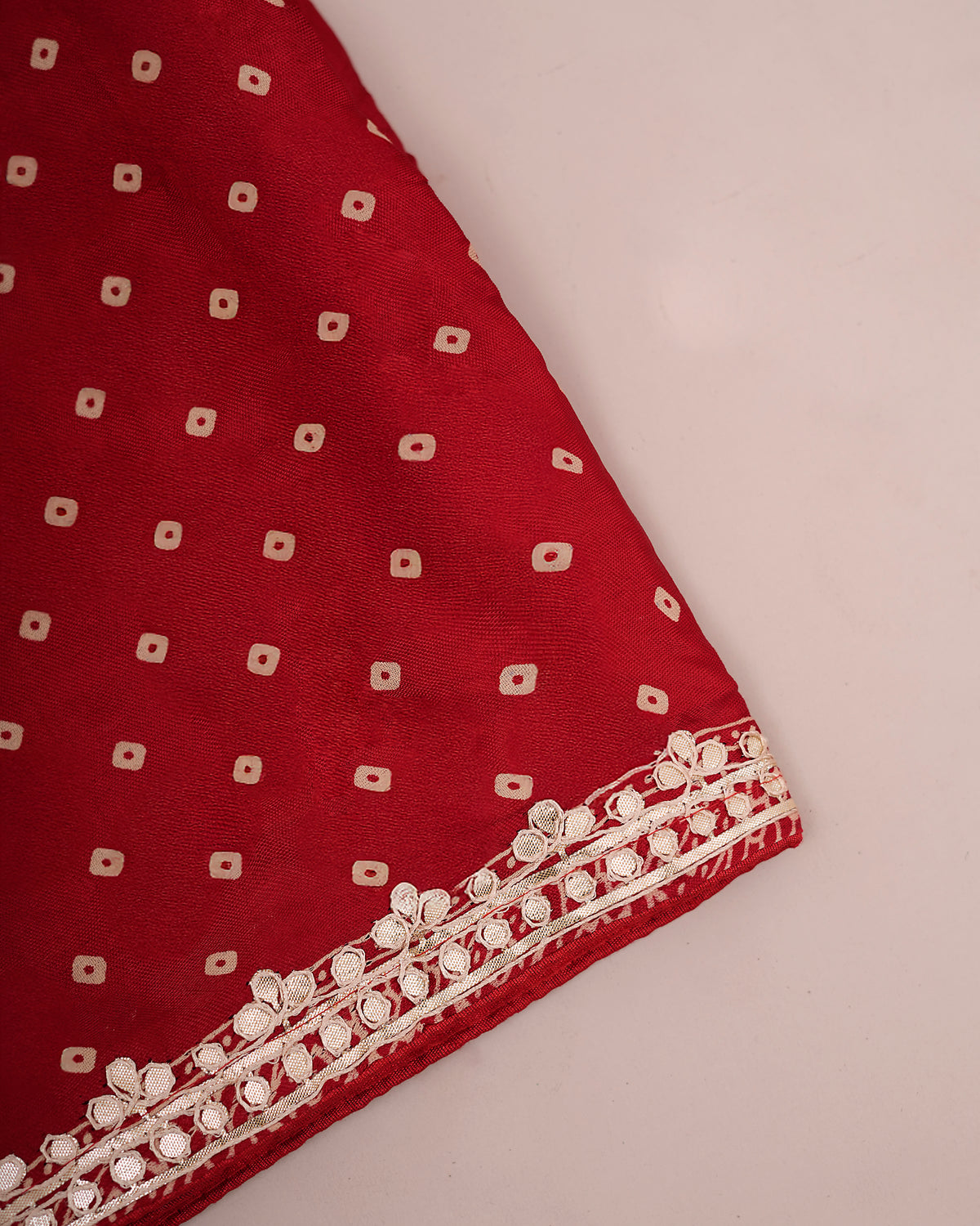 Folded red Bandhani saree fabric showing bandhani print and gota patti border — Chandrikas