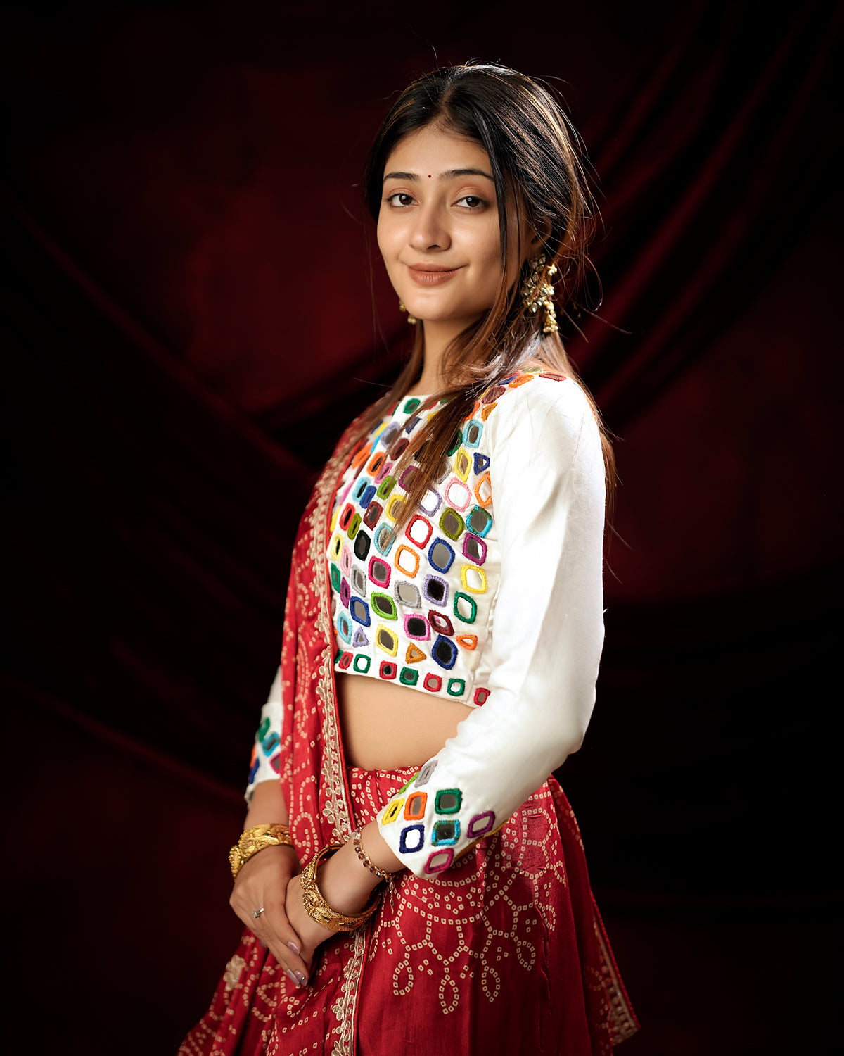 Woman in side standing pose wearing red Bandhani saree with Gota Patti zari border — Chandrikas