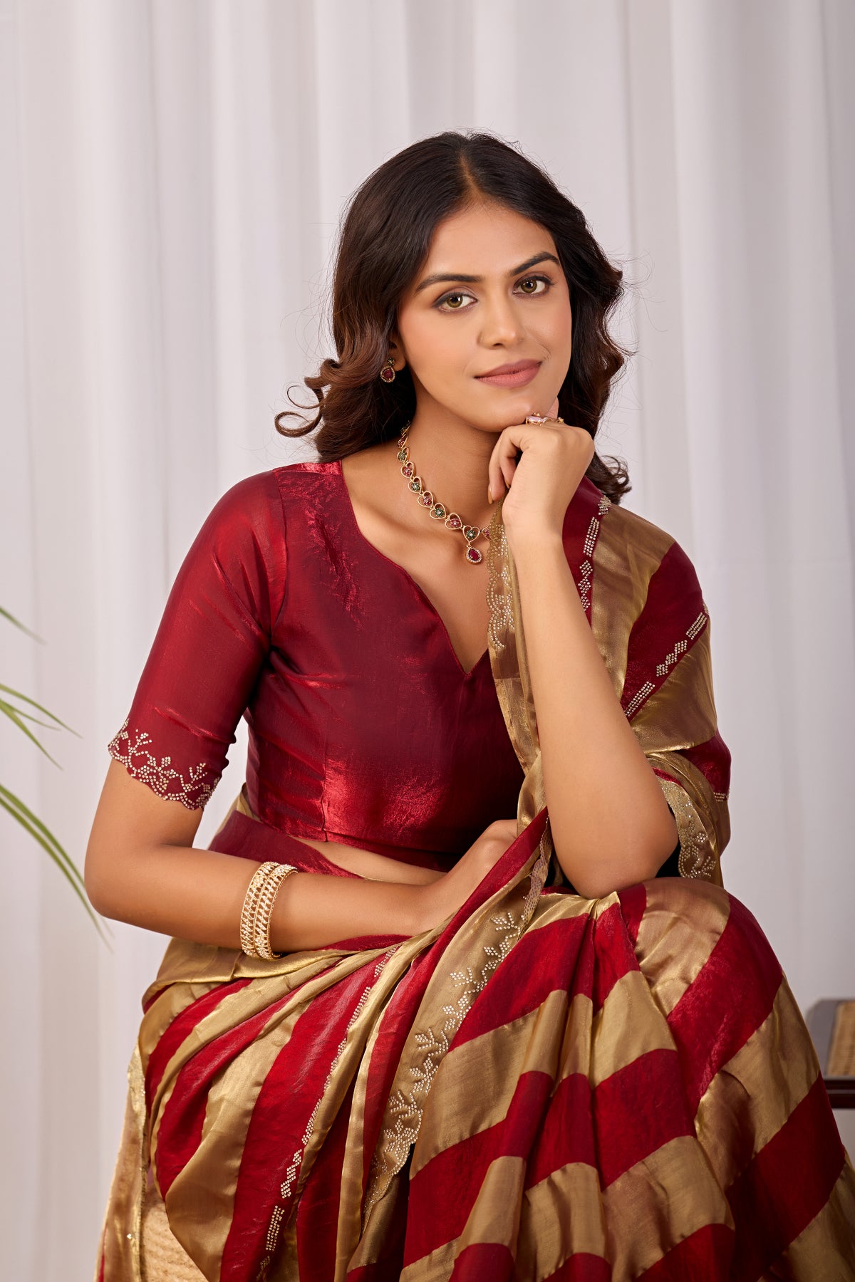 Woman in sitting pose wearing red striped satin patta saree with golden border — Chandrikas
