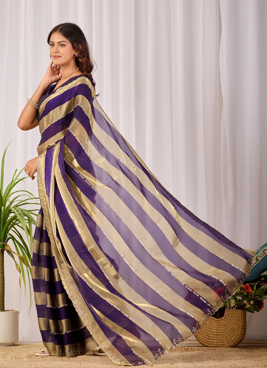 Woman in standing pose wearing royal purple striped satin patta saree with golden pallu — Chandrikas