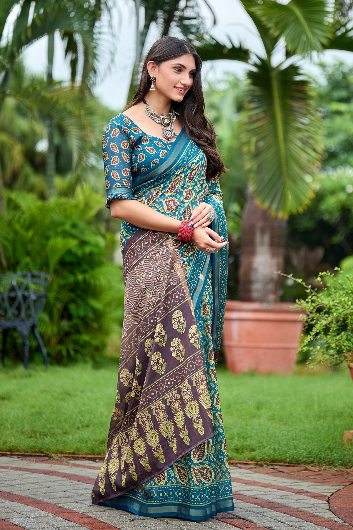 Woman in front pose wearing teal blue leaf print cotton saree with brown border — Chandrikas