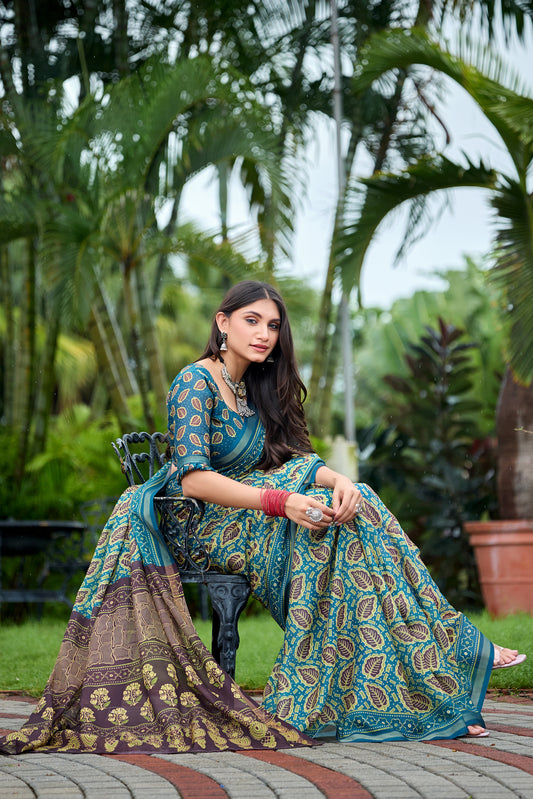 Woman in sitting pose wearing teal blue leaf print cotton saree with brown border — Chandrikas