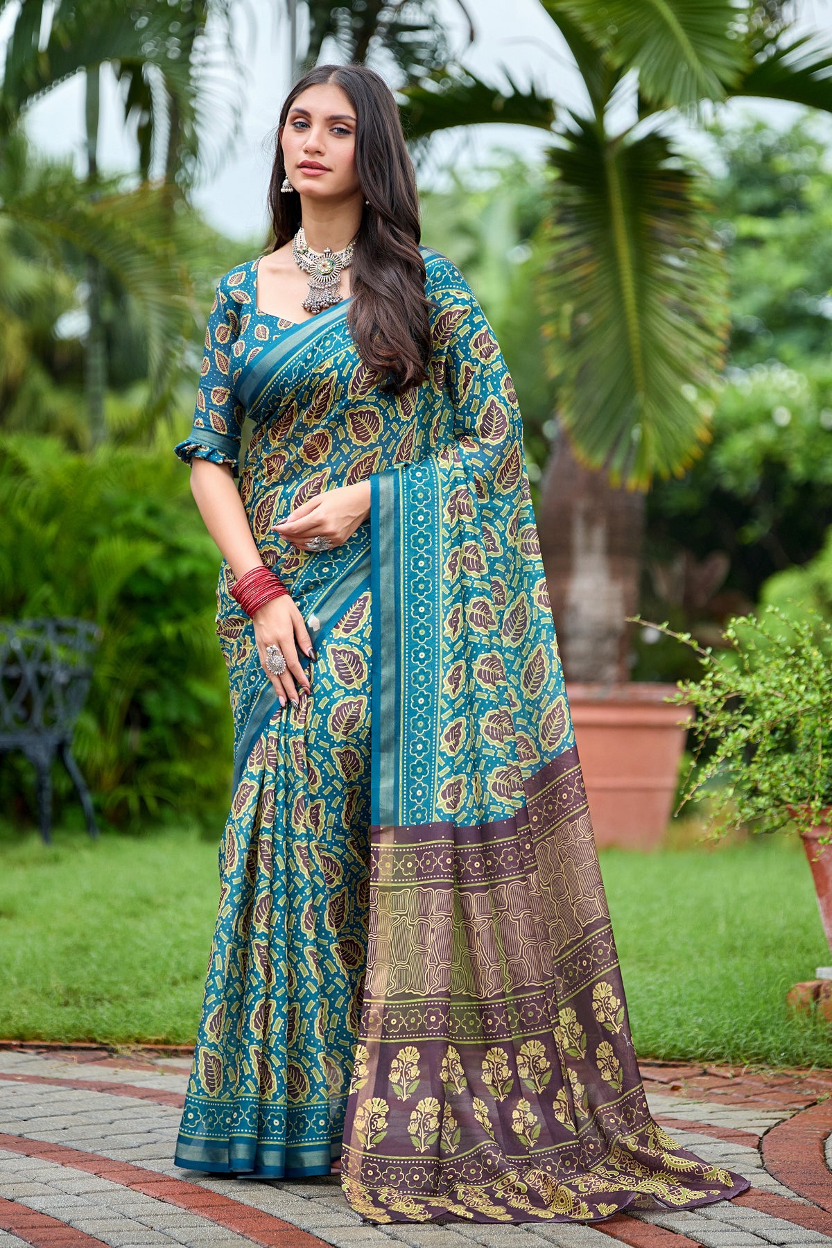 Woman in standing pose wearing teal blue leaf print cotton saree with brown pallu — Chandrikas