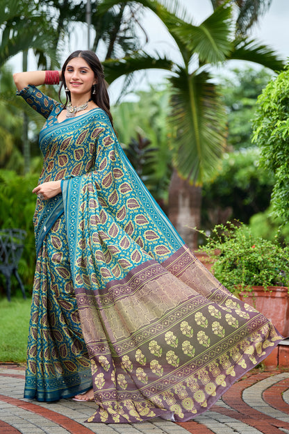 Woman in walking pose wearing teal blue leaf print cotton saree with brown border — Chandrikas